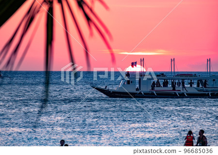 Boracay, Philippines - Jan 21, 2020: Sunset on the background of bottles standing on the bar. The sun passes through the bright glass of the bottles. Background image for the screensaver. 96685036
