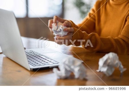 A woman crumpling up miswritten scraps of paper 96685996