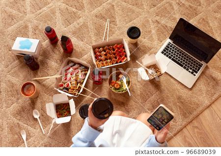 Young woman eating sushi at home. Home food delivery concept. Japan food. Top view. Space for text Young woman eating sushi at home. Home food delivery concept. Japan food. Top view. Space for text 96689039