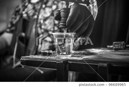 Hand of professional tattoo artist and a tattoo machine. 96689965