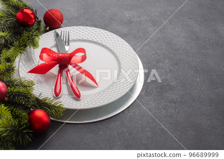 Christmas table setting consisting of a white plate and cutlery tied with a bow. Side view with copy space Christmas table setting consisting of a white plate and cutlery tied with a bow. Side view with copy space 96689999