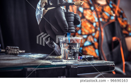 Hand of professional tattooer with a tattoo gun. 96690163