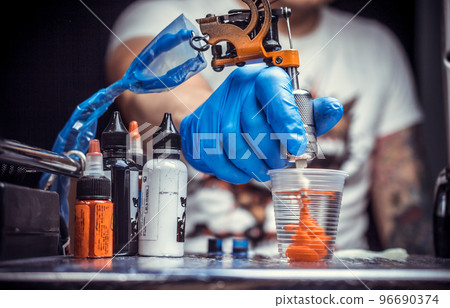 Hand of a tattoo specialist with a tattoo machine. 96690374