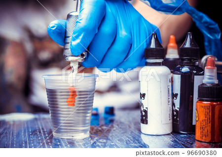 Hand of a tattooer with a tattoo gun. 96690380