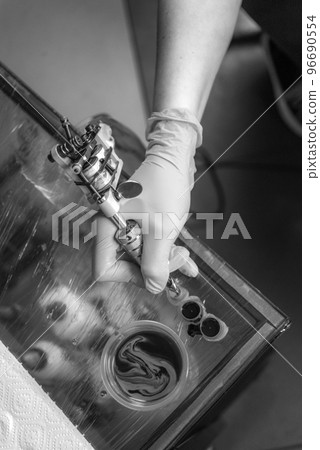 Hand of tattoo master with a tattoo machine. Hand of tattoo master with a tattoo machine. 96690554