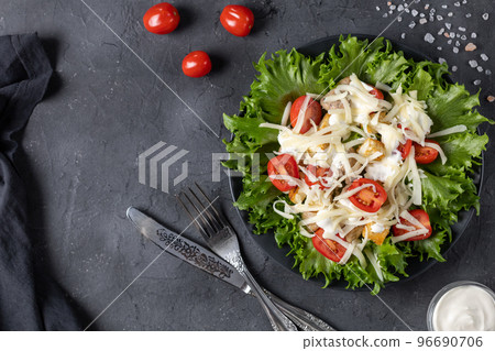 Traditional caesar salad with chicken on a black plate on black table with napkin fork and knife. Traditional caesar salad with chicken on a black plate on black table with napkin fork and knife. 96690706