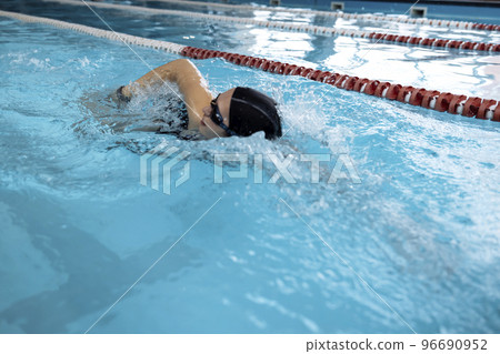 Young swimmer wears a swim cap and puts away goggles 96690952
