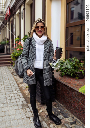 woman with a cup of coffee walking down the street in the city 96693191