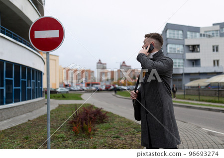 Man talking on the phone next to a parking lot Man talking on the phone next to a parking lot 96693274