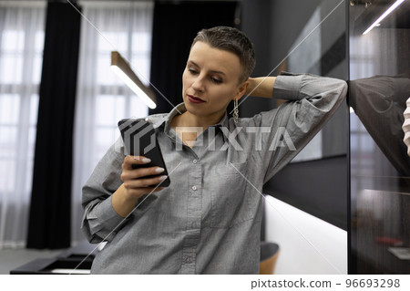 caucasian woman with short haircut holding phone 96693298