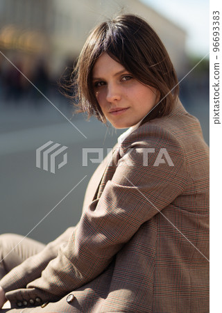 High fashion portrait of young elegant woman in brown suit walk on the street. enjoy summer lights. 96693383