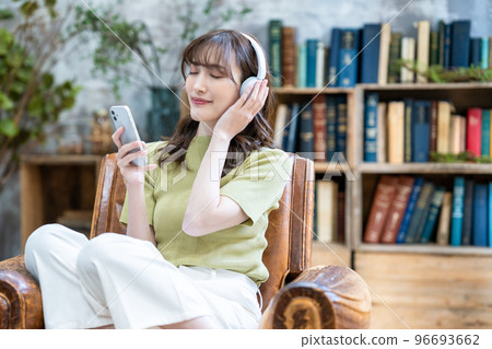 一個戴著耳機在智能手機上聽音樂的女人 96693662