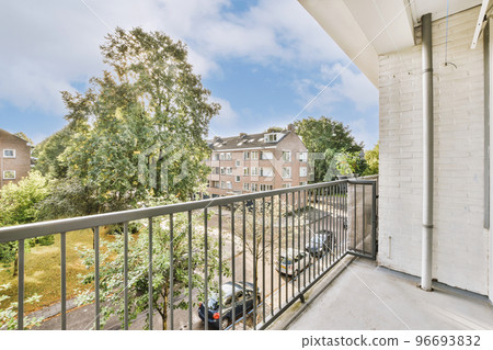 Front view of old brick buildings and cars with bicycles from small balcony with railings 96693832