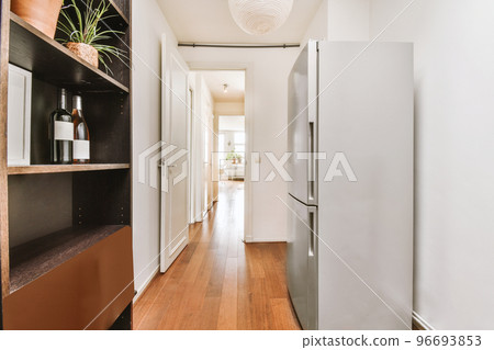 Fragment of interior of light narrow home kitchen with minimalist style white furniture with sink and stove 96693853