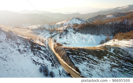 Amazing sunset aerial top drone view of high-speed road between the picturesque mountains in winter. Top down view of picturesque mountain serpentine stretching into the distance. Amazing sunset aerial top drone view of high-speed road between the picturesque mountains in winter. Top down view of picturesque mountain serpentine stretching into the distance. 96695509