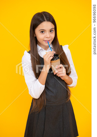 Teenager girl holding a hot cup of coffee or tea. Child with takeaway cup on yellow background, morning energy drink beverage. 96696098
