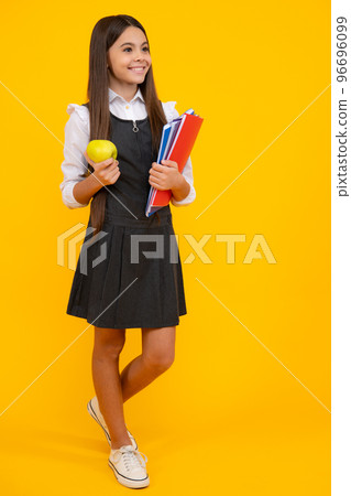 Full length of schoolchild, teenage student girl with school bag backpack hold aplle on yellow isolated studio background. Children school and education concept. 96696099