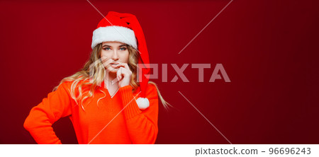 banner. a beautiful woman in a Santa Claus hat thinks on a red background. banner. a beautiful woman in a Santa Claus hat thinks on a red background. 96696243