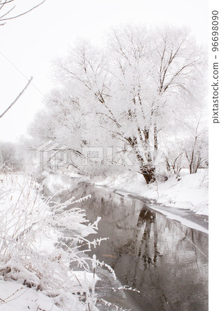 Snow-covered landscape of open spaces near the river. Snowy weather Snow-covered landscape of open spaces near the river. Snowy weather 96698090
