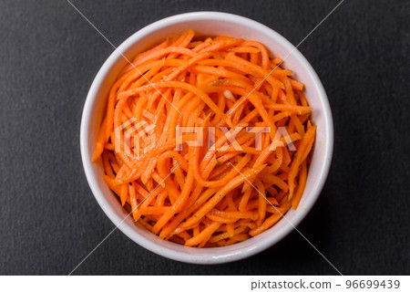 Tasty spicy Korean carrot with spices and herbs on a dark concrete background Tasty spicy Korean carrot with spices and herbs on a dark concrete background 96699439