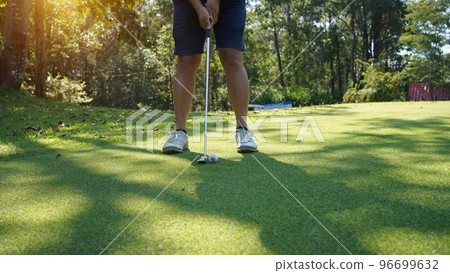 Golfer putting ball on the green golf, lens flare on sun set evening time. 96699632