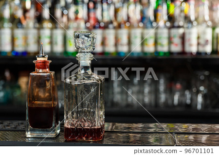 decanters with angostura and sweet liqueur stand in the semi-darkness on the bar counter of a nightclub. 96701101