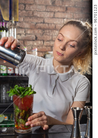 Young beautiful female bartender sprinkles the cocktail with powdered sugar. 96701123
