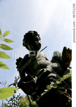 Beautiful Cupid angel statue with wings on back in vintage garden Beautiful Cupid angel statue with wings on back in vintage garden 96701286