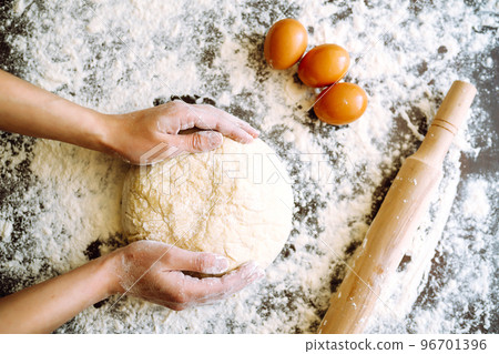 Making dough by female hands on wooden table background. Cooking concept. Lovely female hands. 96701396