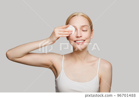 Young attractive smiling woman removing make up on white background Young attractive smiling woman removing make up on white background 96701488