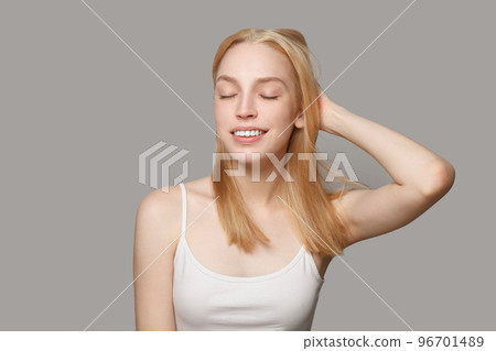Cheerful young woman blonde with long healthy hair and fresh skin smiling on white background Cheerful young woman blonde with long healthy hair and fresh skin smiling on white background 96701489