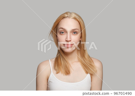 Attractive young woman with blonde hairstyle and natural makeup looking at camera Attractive young woman with blonde hairstyle and natural makeup looking at camera 96701490