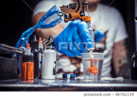 Hand of a tattoo artist with a tattoo gun. 96702139