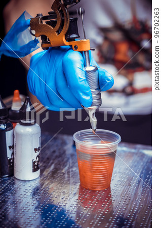 Hand of a tattooer, holding a tattoo machine. 96702263