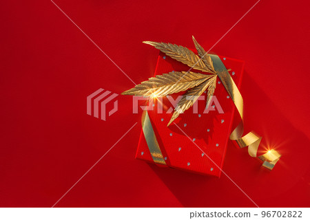 Christmas background with gift box, golden leaf marijuana red festive background Christmas background with gift box, golden leaf marijuana red festive background 96702822