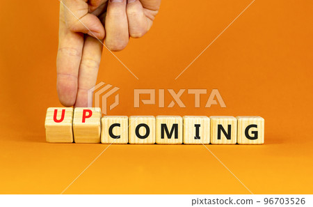 Coming or upcoming symbol. Concept words Coming and Upcoming on wooden cubes. Businessman hand. Beautiful orange table orange background. Business coming or upcoming concept. Copy space. Coming or upcoming symbol. Concept words Coming and Upcoming on wooden cubes. Businessman hand. Beautiful orange table orange background. Business coming or upcoming concept. Copy space. 96703526