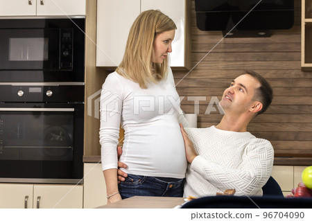 Man touches, holds hand on big belly of pregnant woman, feeling baby movement. Happy parenthood, child expectation 96704090