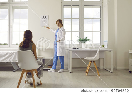 Oculist or ophthalmologist pointing at eye chart while checking child's eyesight 96704260