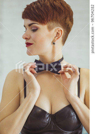 slim woman in a leather dress straightens a butterfly around her neck 96704282