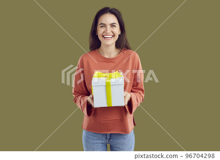 Happy laughing brunette woman in red sweatshirt is holding a present in hands on khaki background. Happy laughing brunette woman in red sweatshirt is holding a present in hands on khaki background. 96704298