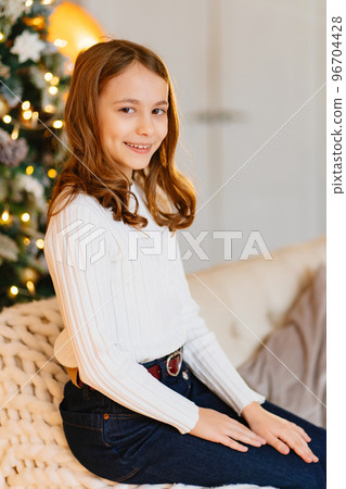 a cute teen girl with dark hair in a white chair with a knitted blanket.  96704428