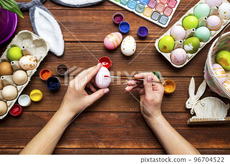 A woman with a tassel paints Easter eggs. Preparing decorations for Easter A woman with a tassel paints Easter eggs. Preparing decorations for Easter 96704522