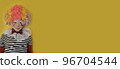 A boy in a clown costume on the background of a bright yellow wall is fooling around and smiling 96704544