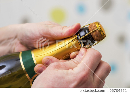 Mans hands open the bottle of champagne on party celebration event Mans hands open the bottle of champagne on party celebration event 96704551