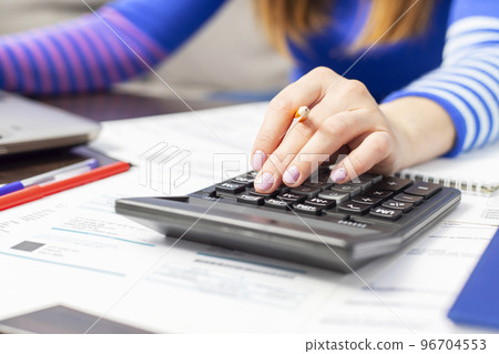 Woman using calculator for calculate domestic bills at home 96704553