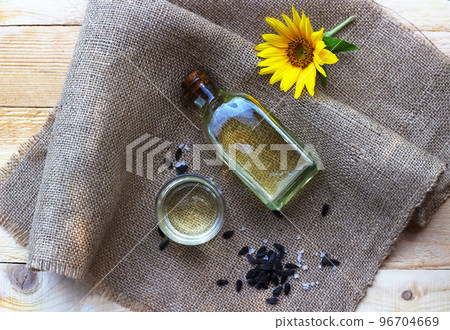 Close-up of sunflower oil in a bottle glass with seeds on burlap canvas fabric background. Top view. 96704669