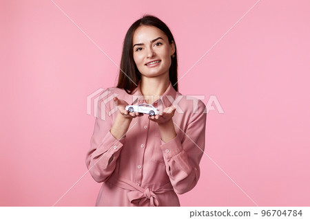 beautiful woman in dress holding little white car 96704784