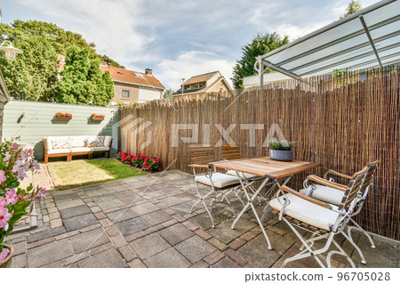 Neat powerful patio with sitting area and small garden near wooden fence 96705028