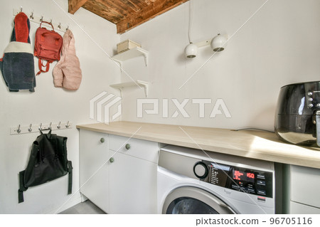 Interior of light kitchen with modern cupboards and appliances located near dining room in modern flat at daytime Interior of light kitchen with modern cupboards and appliances located near dining room in modern flat at daytime 96705116