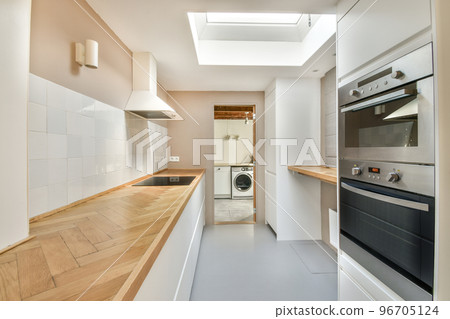 Interior of light kitchen with modern cupboards and appliances located near dining room in modern flat at daytime 96705124